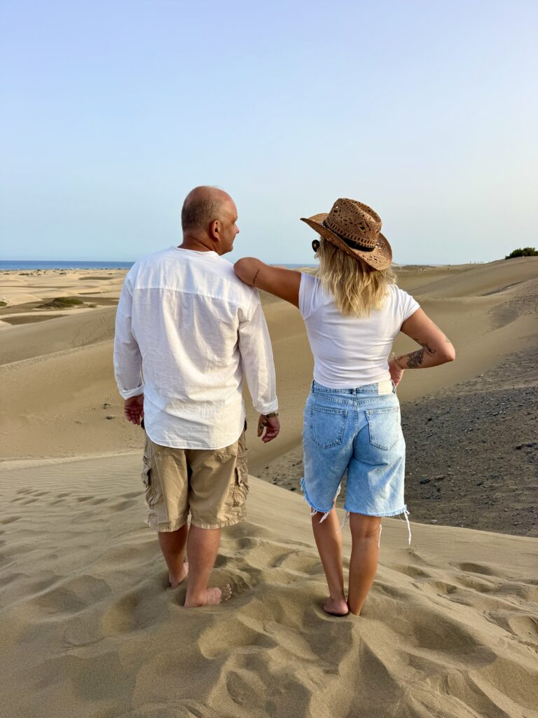 Maciej i Julia Dybczyńscy stoją tyłem na wydmach nad morzem